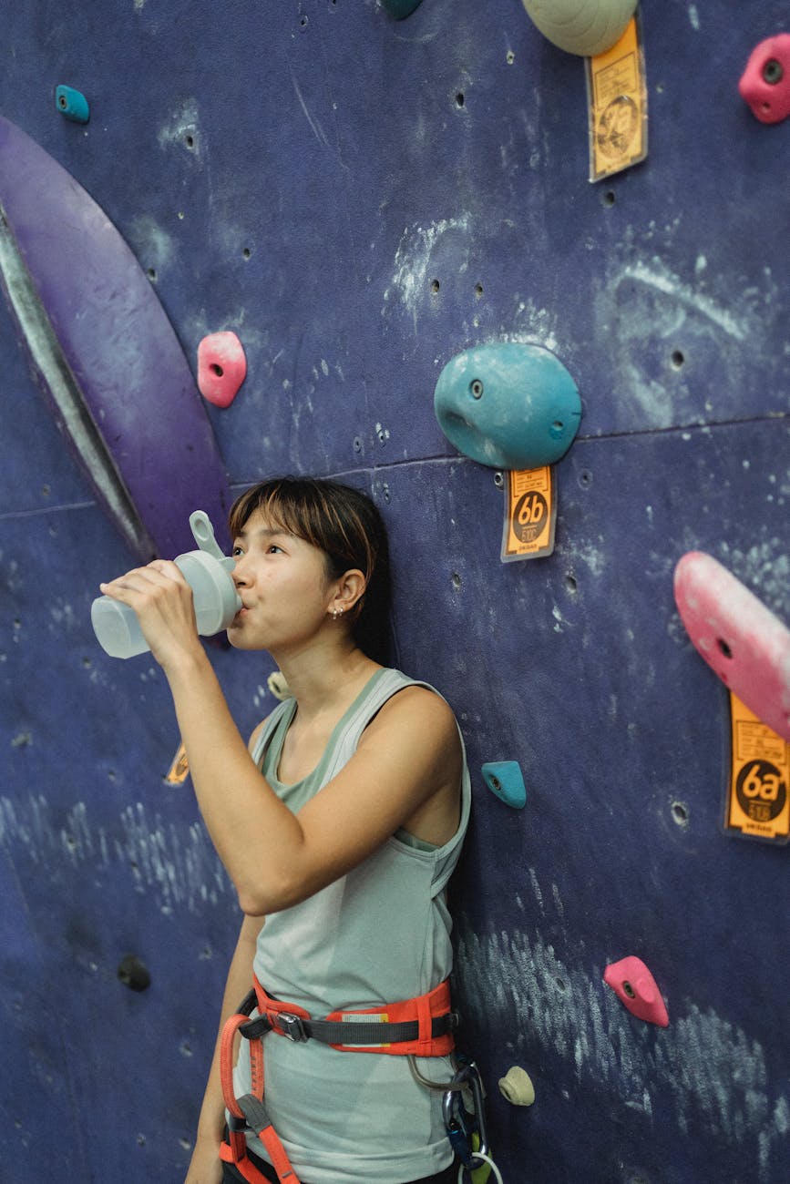Beat the Heat: Safe Summer Workout Tips for Filipino Fitness Enthusiasts 1 asian female climber drinking water near climbing wall