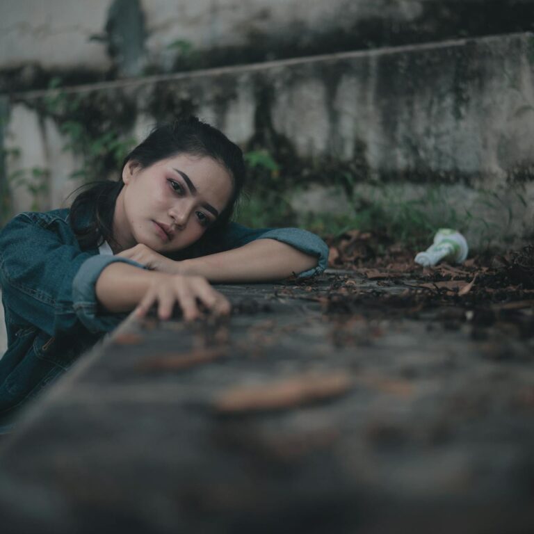 pensive teen aged girl sitting near stone fence